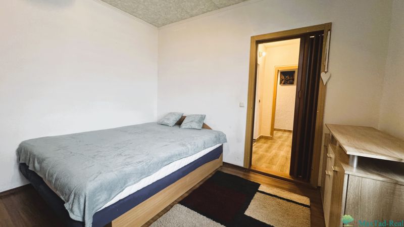A bedroom in a 4-room apartment with a bed, carpet, and furniture with a wooden decor.