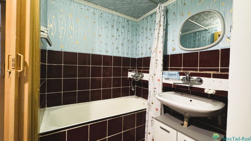 A bathroom with an enameled bathtub and tiled walls in a 4-room apartment.