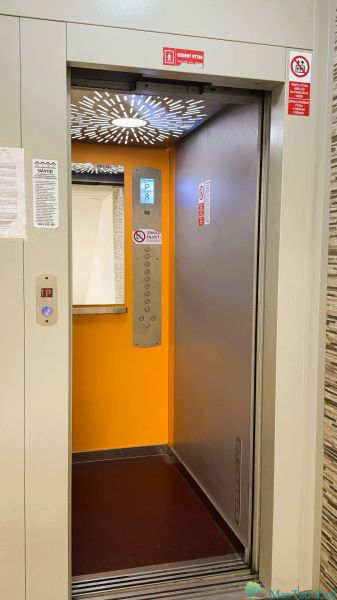 Open elevator in a 4-room apartment building with an orange interior.