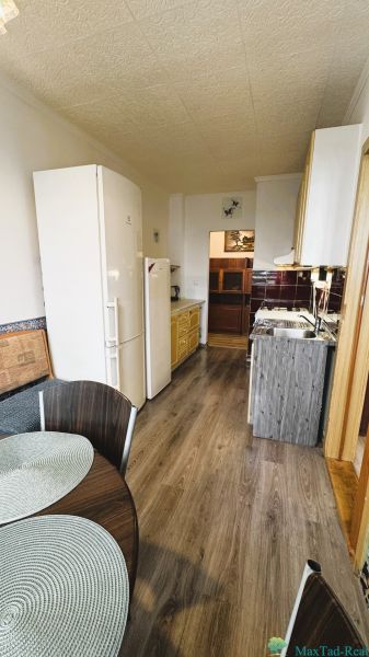 A kitchen in a 4-room apartment with a wood-patterned floor, a dining table, and appliances.