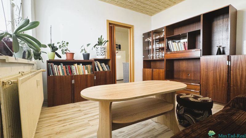 Living room with cabinets, books, flowers, and a wooden decor floor in a 4-room apartment.