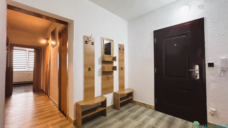 Entrance hall with a mirror and a coat rack, 4-room apartment with wood-patterned flooring.