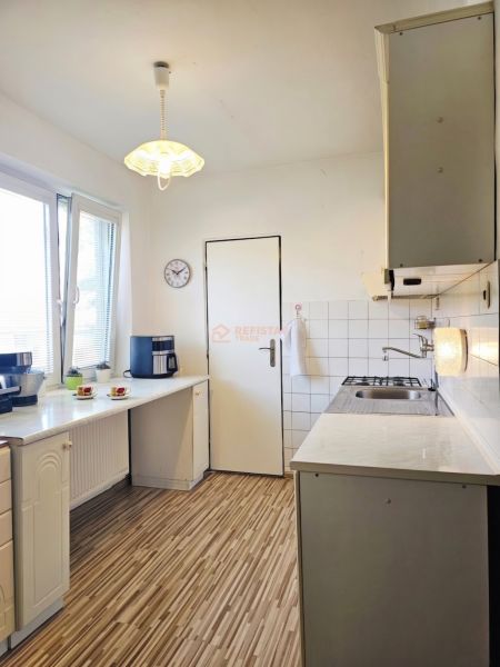A kitchen in a family house with a wooden decor floor and white cabinets.