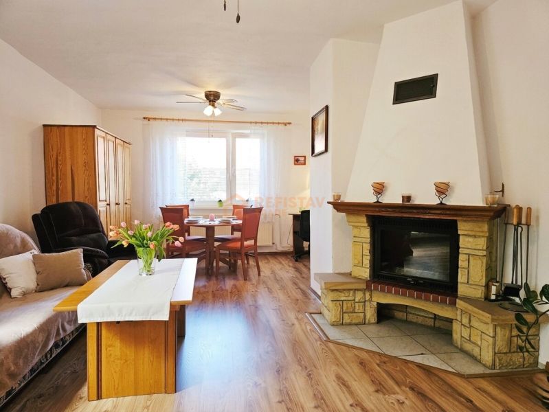 A room in a family house with a fireplace, a sofa set, and a floor with a wooden decor.