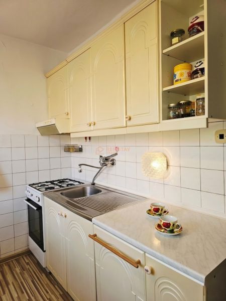 A kitchen in a family house with white cabinets and a counter, and a floor with a wooden decor.