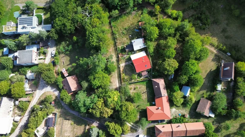 An aerial view of gardens and houses in Kolačno, surrounded by dense greenery.