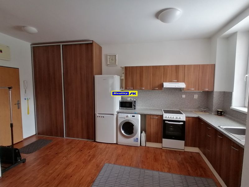 A kitchen in a 2-room apartment, wooden decor on the floor and kitchen unit.