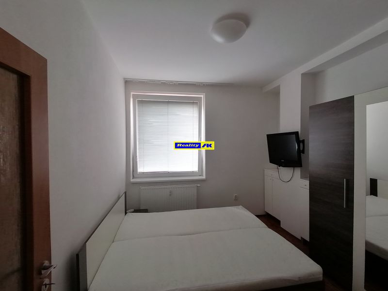 A bedroom in a 2-room apartment with a TV and a bed.
