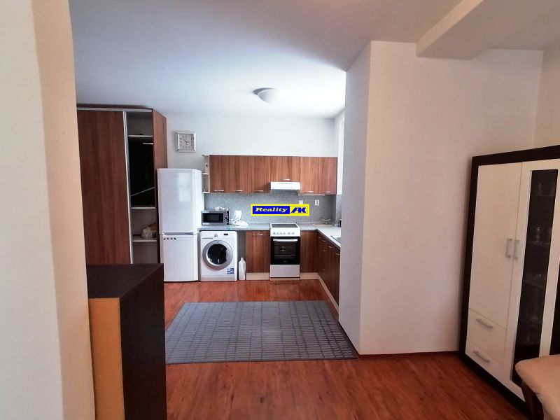 A kitchen with a wooden decor floor in a 2-room apartment, appliances, cabinets, carpet.