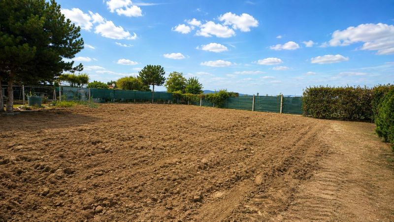 Residential plots in Pravotice with cultivated land, green hedges, and blue skies.