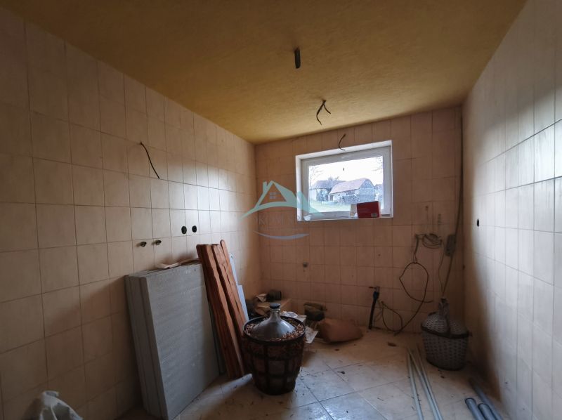Room in a family house with tiles, a window, building materials, and furnishings.