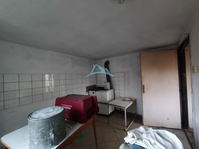 A room in a family house with a table, a bucket, and tiles on the wall.