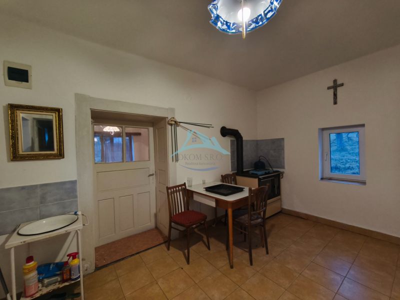 A kitchen in a family house with a stove, a simple table, and a chair.