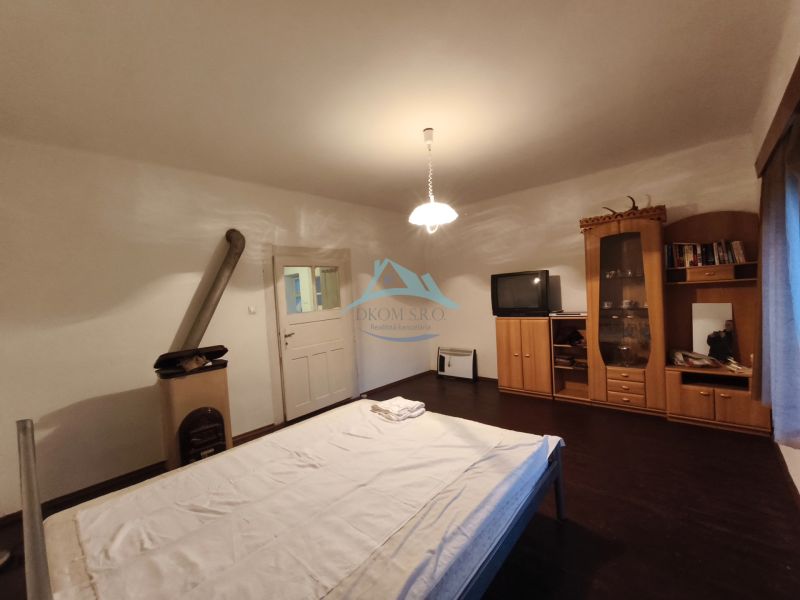 A bedroom in a family house with a dark floor, furniture, a television, and a stove.