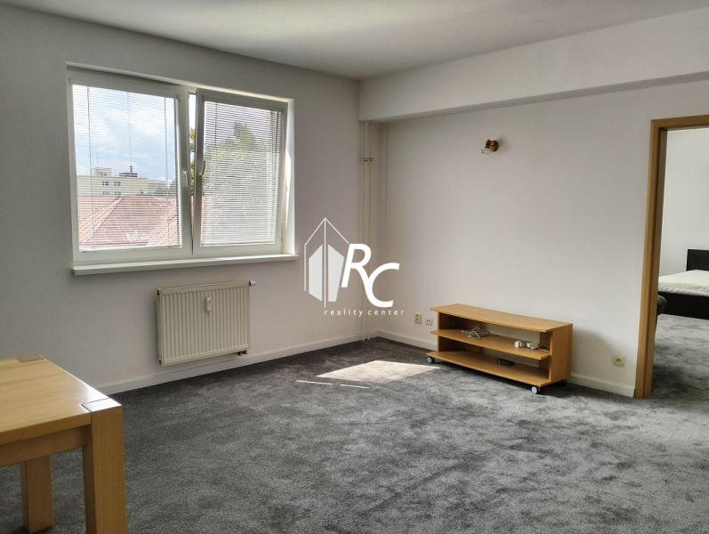 A bright living room with a carpet and furniture in a 2-room apartment.
