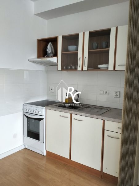 A kitchen with white cabinets in a two-room apartment, a floor with a wooden decor.