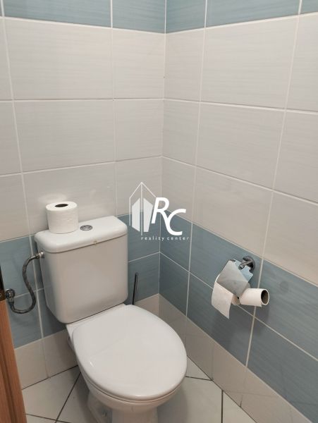 A bathroom with light tiles and a toilet in a 2-room apartment.