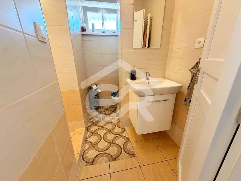 A bathroom with beige tiles and a wooden decor floor in a family house.