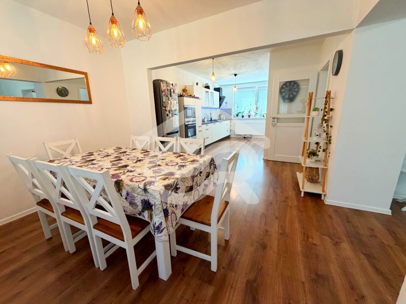 Dining room with wood-patterned flooring in a family house, with chairs and a dining table.