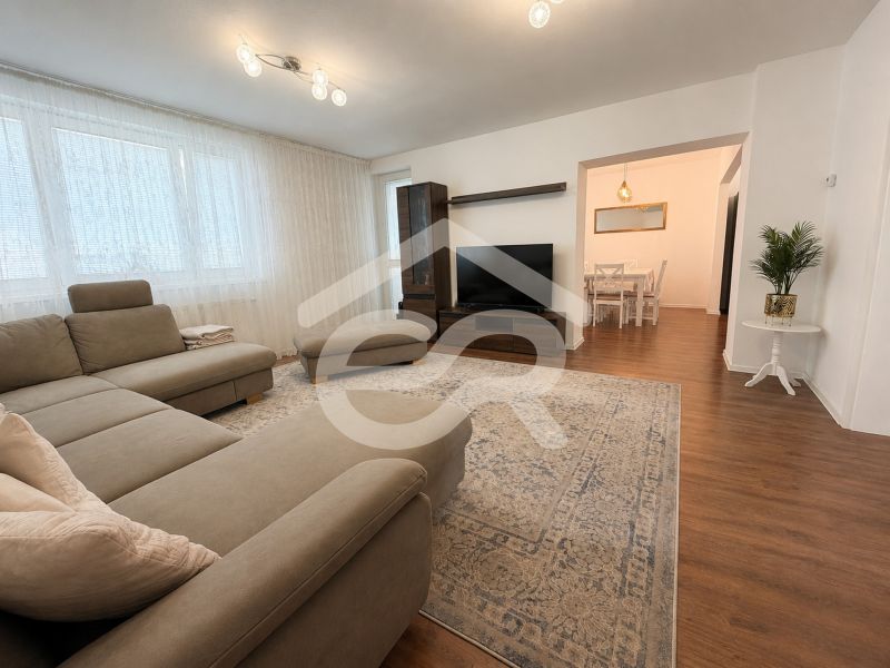 Bright living room with a corner sofa and a wooden decor floor in a family house.