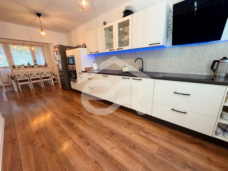 A kitchen with a wood-patterned floor, white cabinets, and a dining table in a family house.