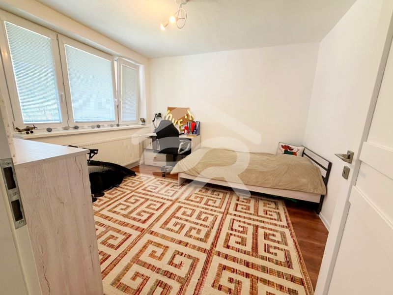 A room in a family house with a carpet pattern and a wooden decor floor.