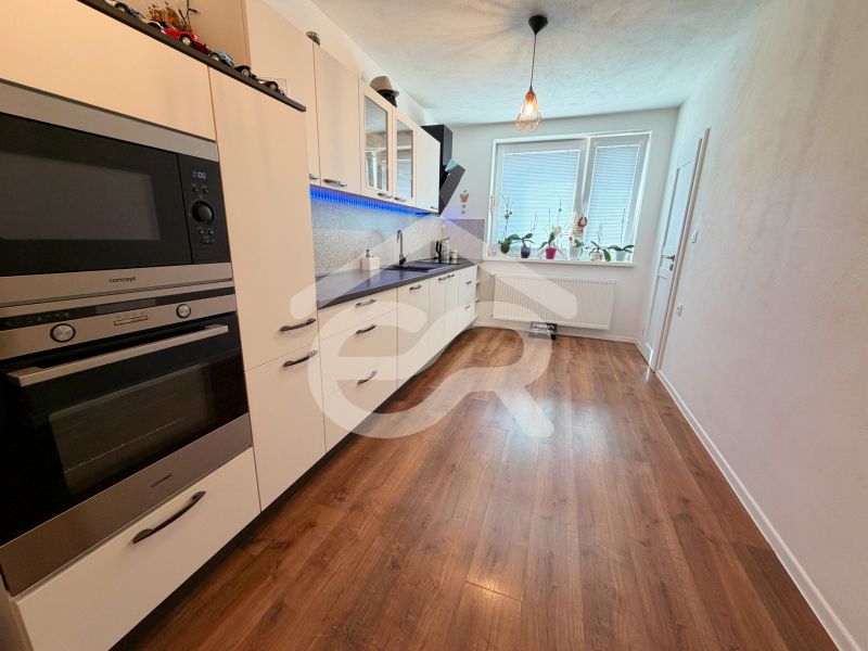 A kitchen in a family house with white cabinets and a floor with a wooden decor.