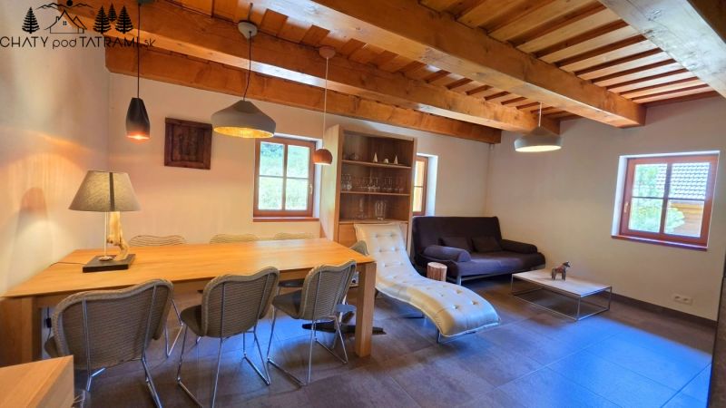 The interior of a cabin with a wood-decorated ceiling, comfortable furniture, and decorative lighting.