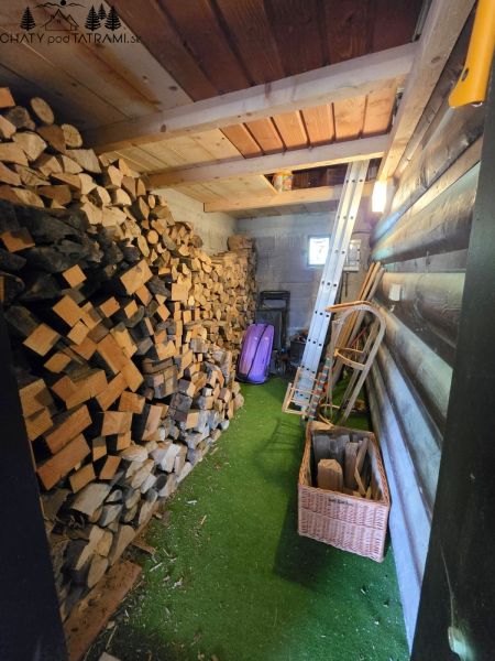 Wooden interior of a cabin with a supply of wood and tools.
