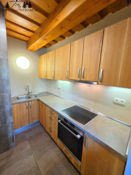 A kitchen in a cottage with a wooden ceiling and a floor with a wooden decor.