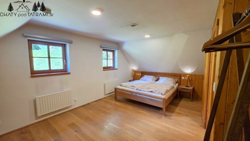 A room in a cabin with a wooden decor floor and a double bed.
