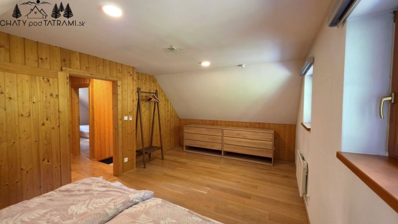 A room in a cabin with a wooden decor floor, wooden paneling, and minimalist furniture.