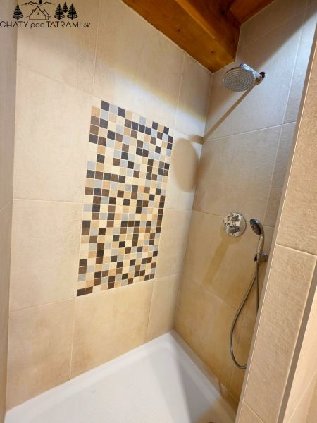 A shower corner with mosaic on the wall in a cottage.