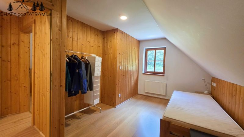 A room with wooden paneling and a floor with a wood decor, a bed and a window.