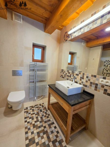 Bathroom in a cabin with a shower, sink, toilet, and mosaic tiles.