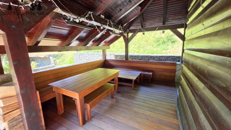The exterior of the cottage in Jarabej with a wooden shelter and seating area.