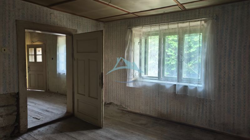 An old interior in a family house with wooden flooring and curtains on the windows.