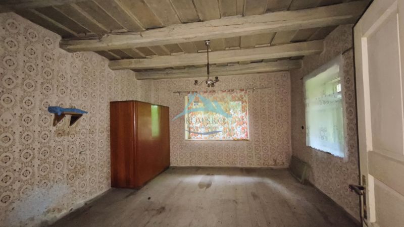 Old wallpaper, wooden ceiling, shelf, and wardrobe in a room of a family house.