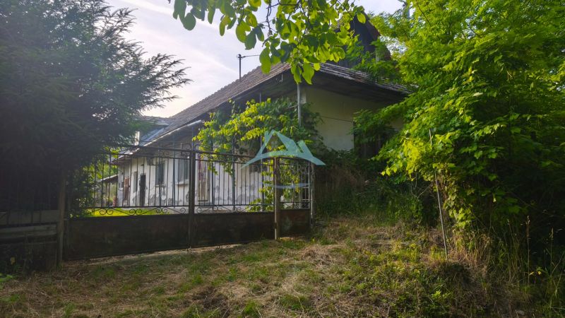 A family house in Čelovce surrounded by greenery and a metal fence.