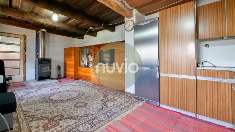Interior of a family house with a fireplace and wooden ceiling, complemented by a carpet and a bookshelf.