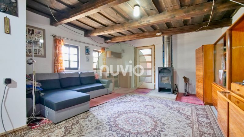 Living room in a family house with a wooden ceiling, sofa, and tiled stove.