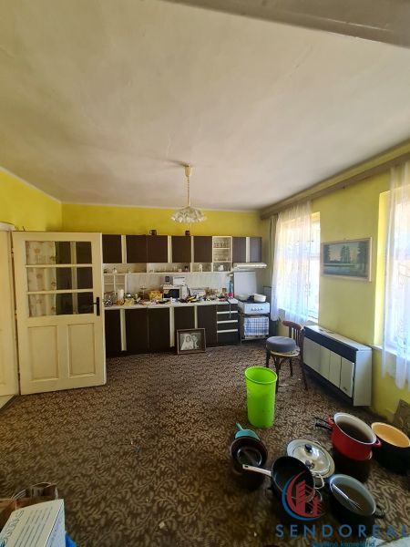 A kitchen in a family house with yellow walls, a brown carpet, and a kitchen unit in Dolné Otrokovce.