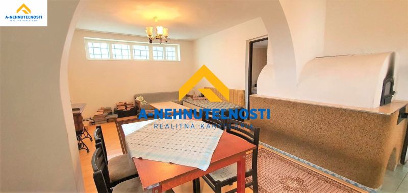 Interior of a family house with a tiled stove, table, chairs, and a floor with a wooden decor.