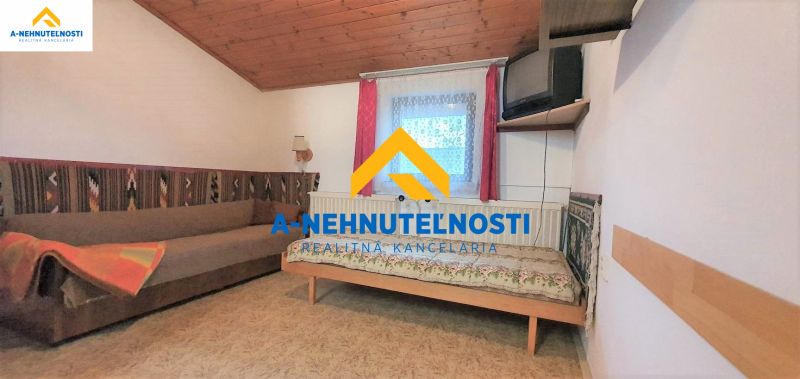 A room in a family house with a sofa, bed, and a TV on the wall.