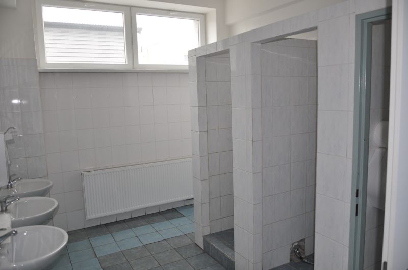 A bathroom in a production area with a tiled floor and several sinks.