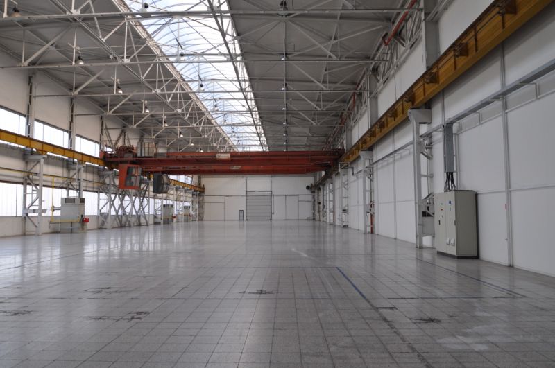 Spacious manufacturing spaces with high ceilings and concrete floors.