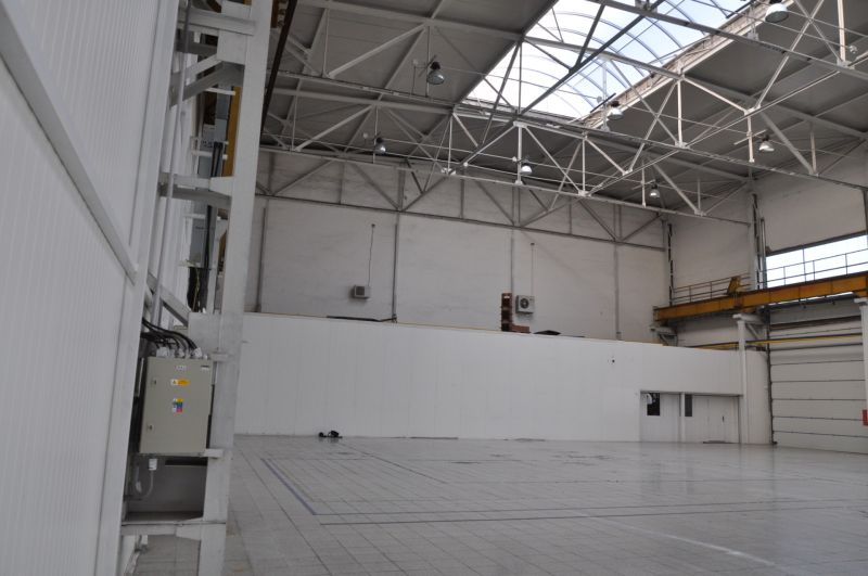 Interior of manufacturing spaces with high ceilings, flooring, and natural light from the roof.