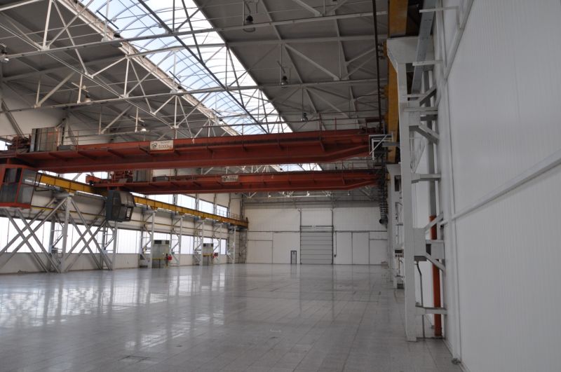 An industrial hall in production premises with two cranes and a glass roof.
