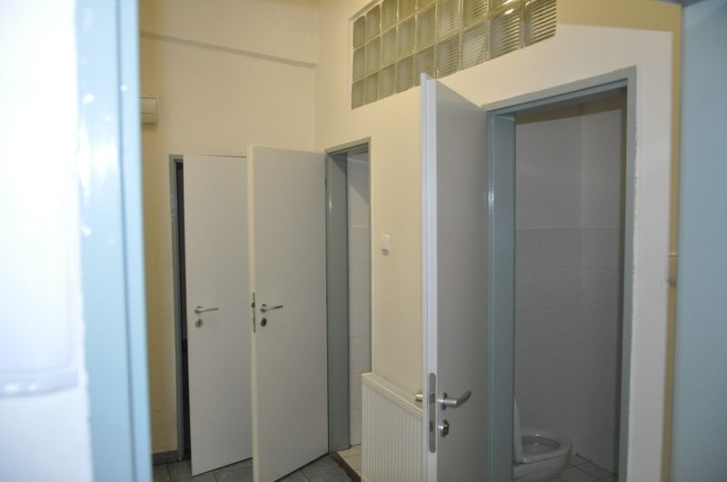 Open door to the restroom in the production area with tiles and a sink.