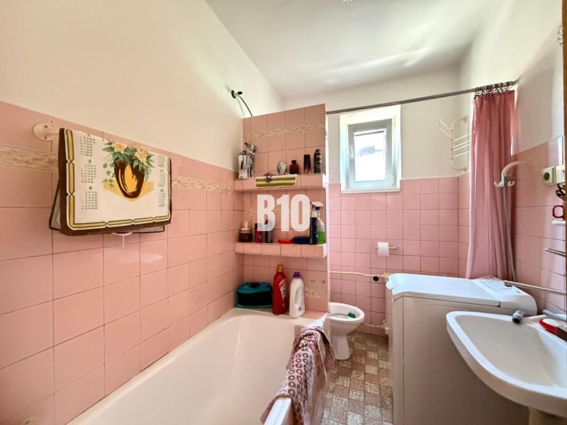 A bathroom in a family house with pink tiles and a bathtub.
